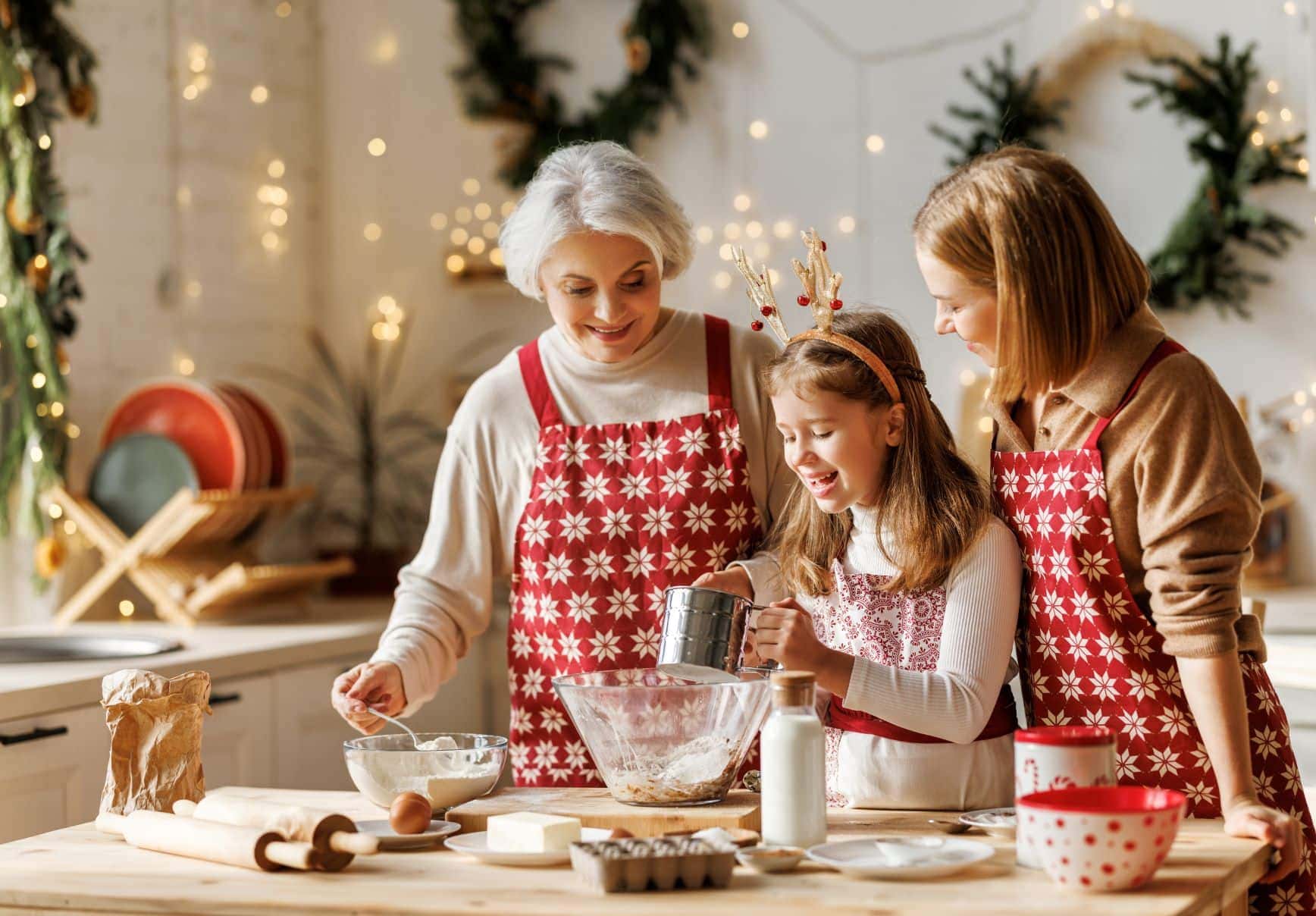 elderly woman, adult woman, and young girl making cookies together