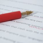 Red pen on essay with corrective marks.