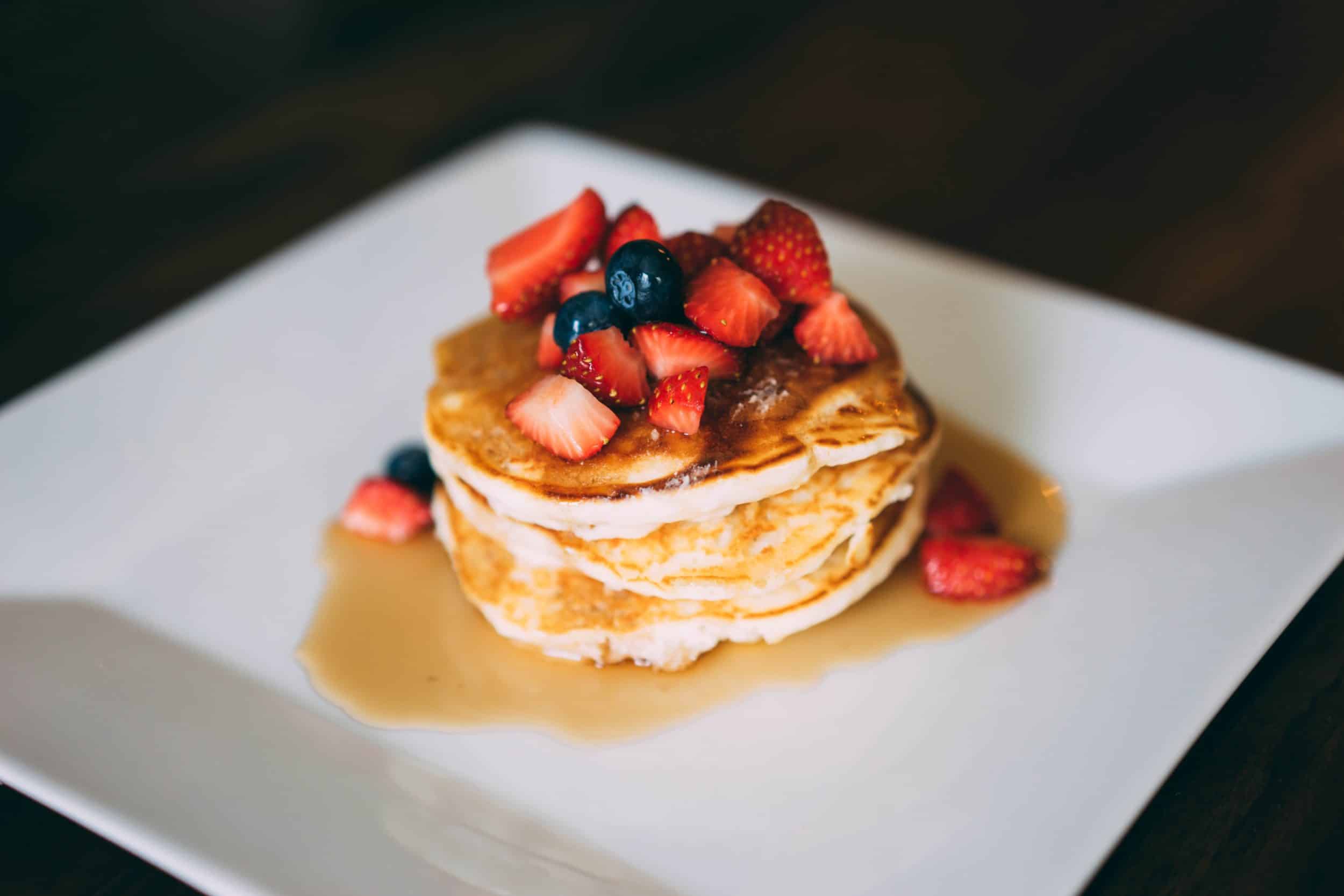pancakes topped with syrup and berries on white plate