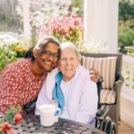 caretaker and resident sitting at table in gardens
