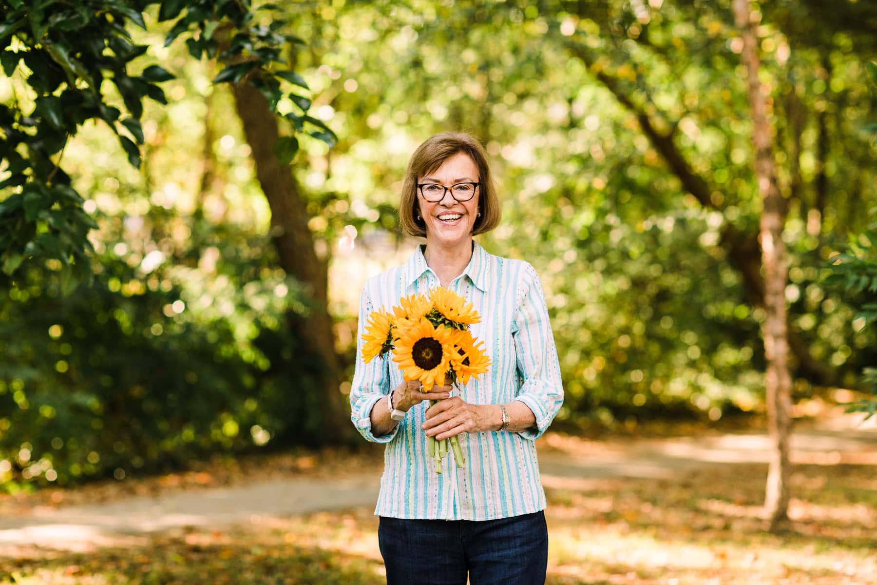 a woman holding sunflowers outside