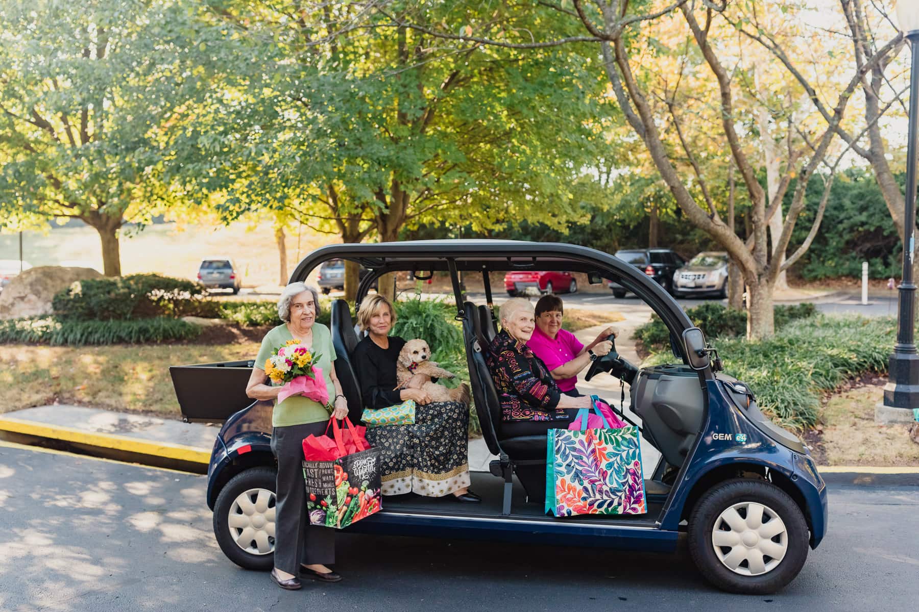 people in a car holding groceries, flowers and smiling outside