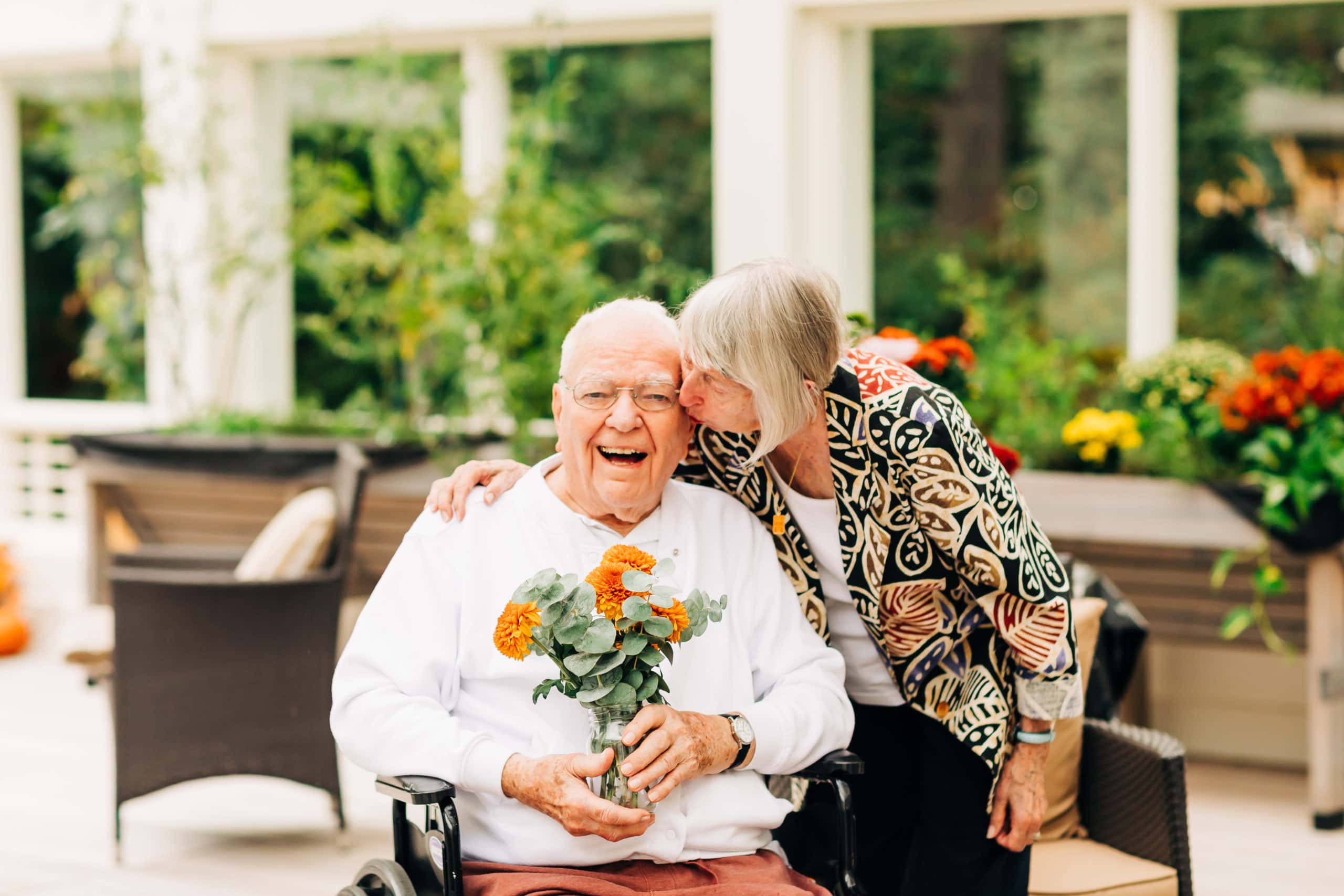 senior couple smiling and holding flowers
