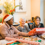 senior women and caregiver wrapping holiday gifts