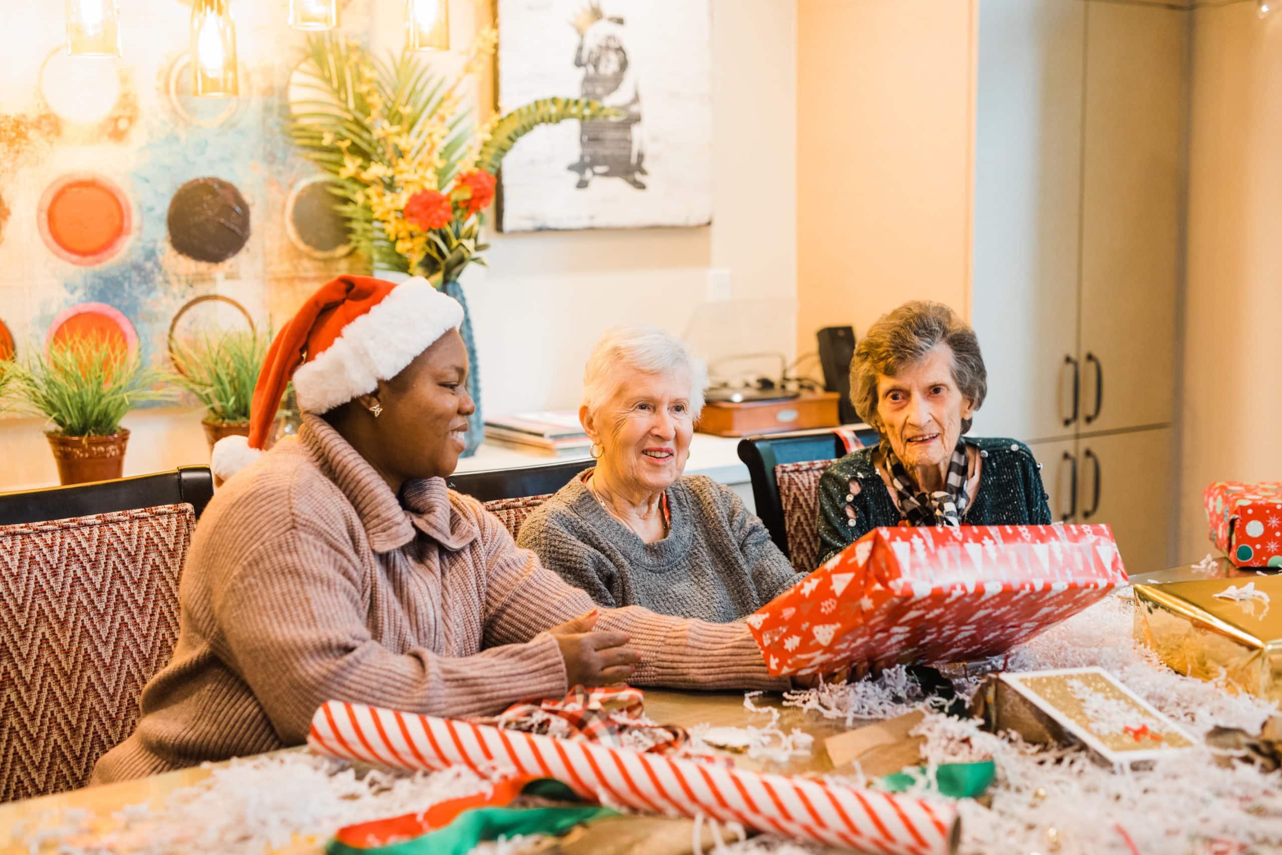 senior women and caregiver wrapping holiday gifts