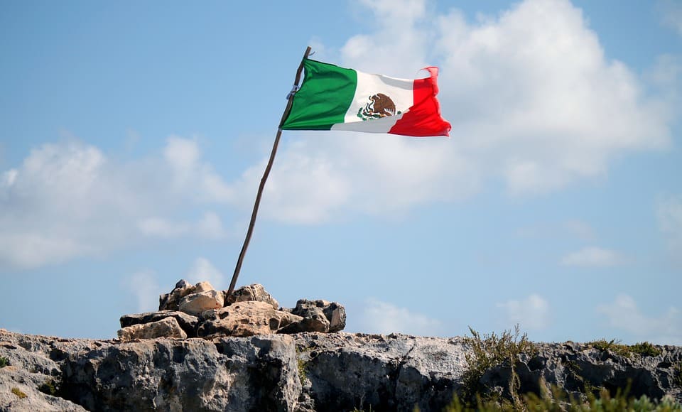 Mexican flag against a blue sky.