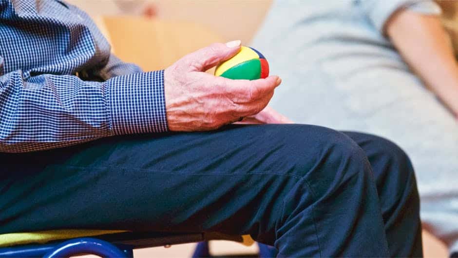 Seated senior holding exercise ball.
