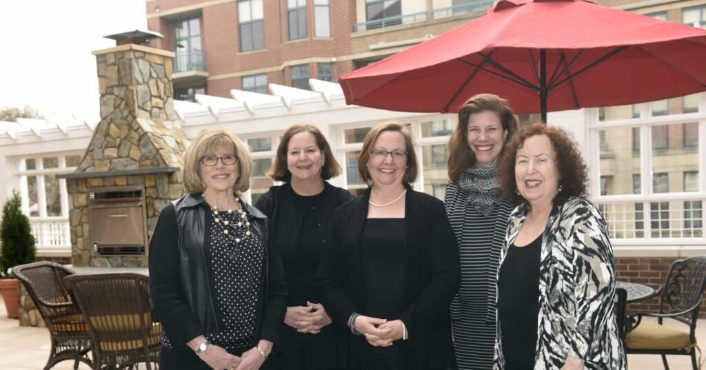 The Kensington Falls Church Team of Directors Standing Together Against a Backdrop of the City of Falls Church.