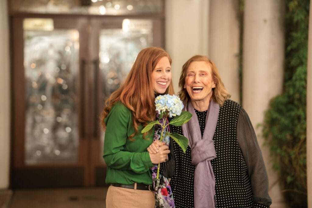 two women holding a flower